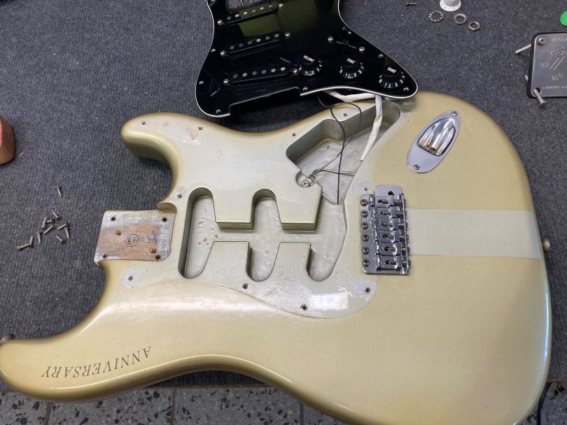 The original Silver finish is preserved under the pickguard, and it is also visible behind the bridge where the sticker was.