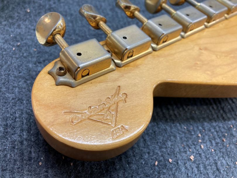 The first Custom Shop models featured the logo stamped into the wood on the back of the headstock