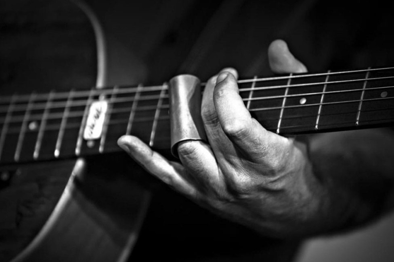 The typical sliding sound of a slide guitar is created by a piece of hollow tube called a slide, or bottleneck, which the guitarist wears on a finger of their left hand. I Photo: Paolo Piga