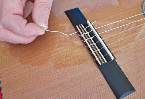 Unlike metal strings, nylon strings are tied to the bridge.
